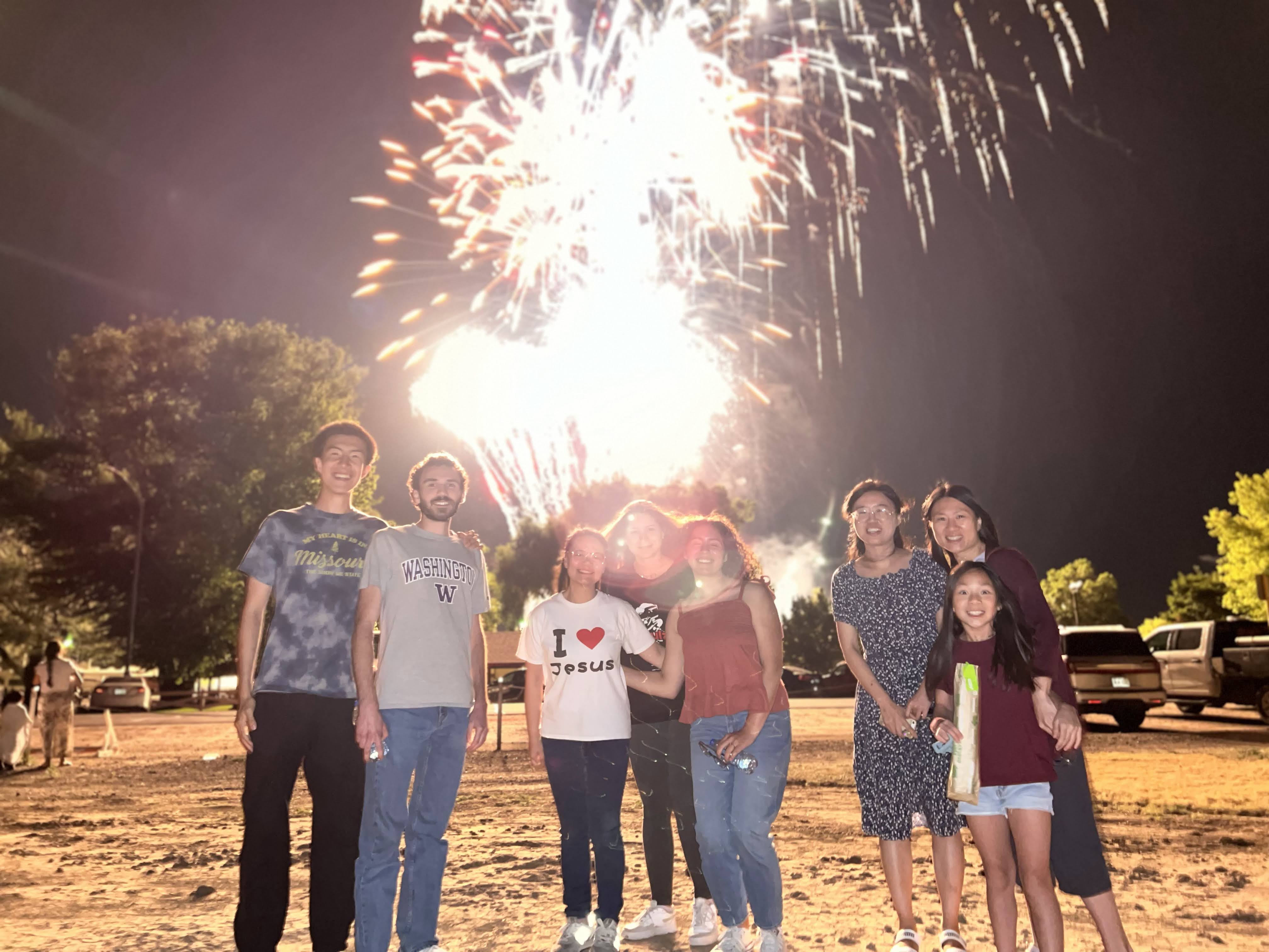 Young Disciples members gathered together outdoors at night as fireworks light up the sky